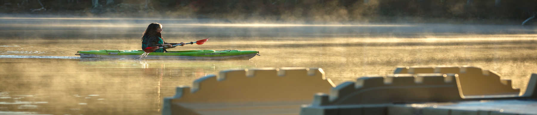 Woman paddling in foggy lake