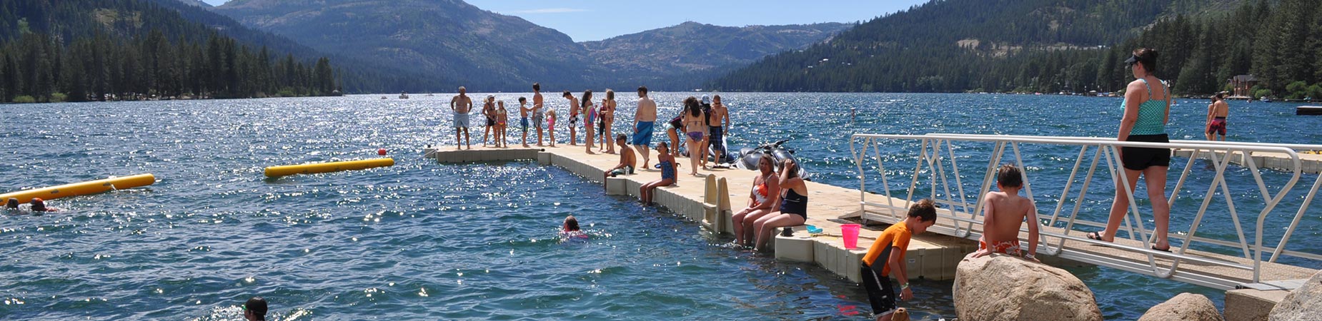 Group of people standing and swimming around floating dock