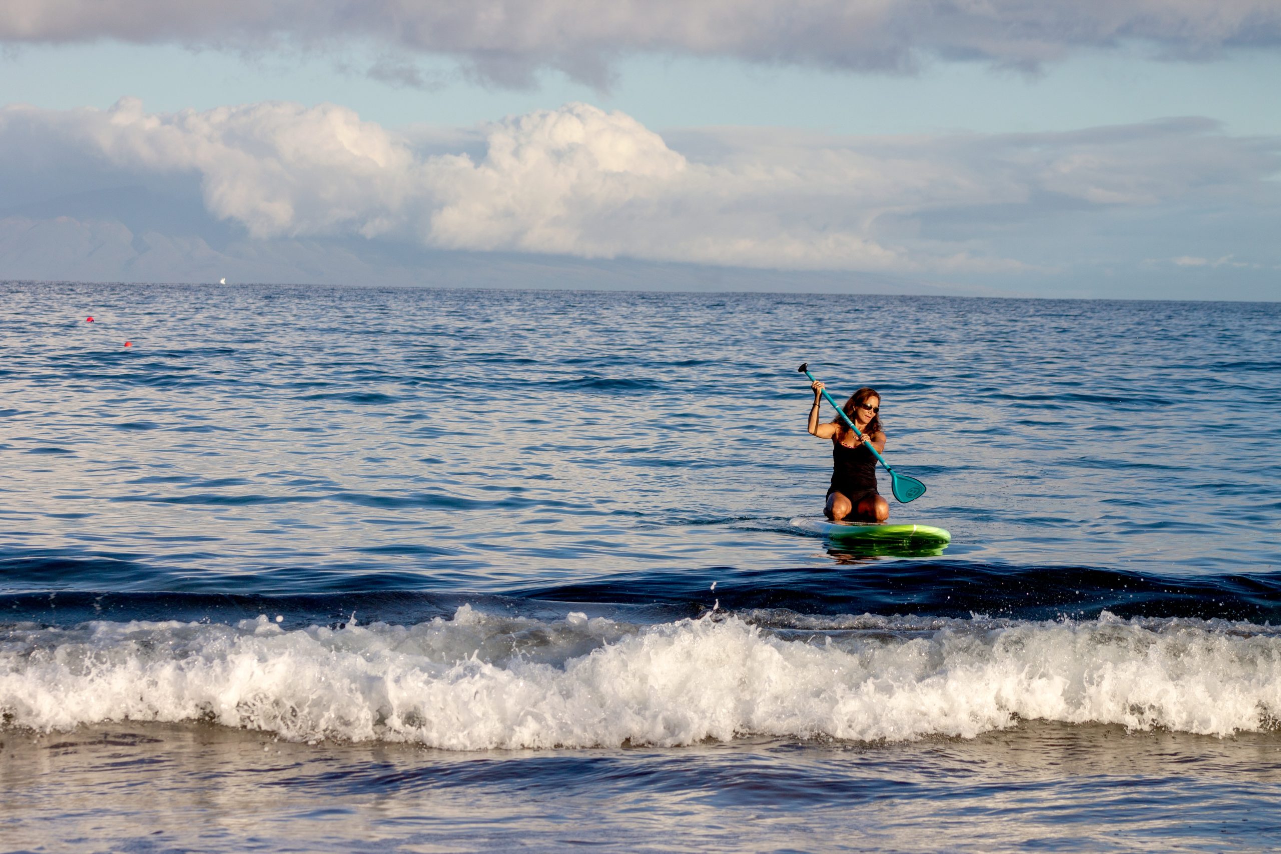 Woman kneeling on paddleboard on beach