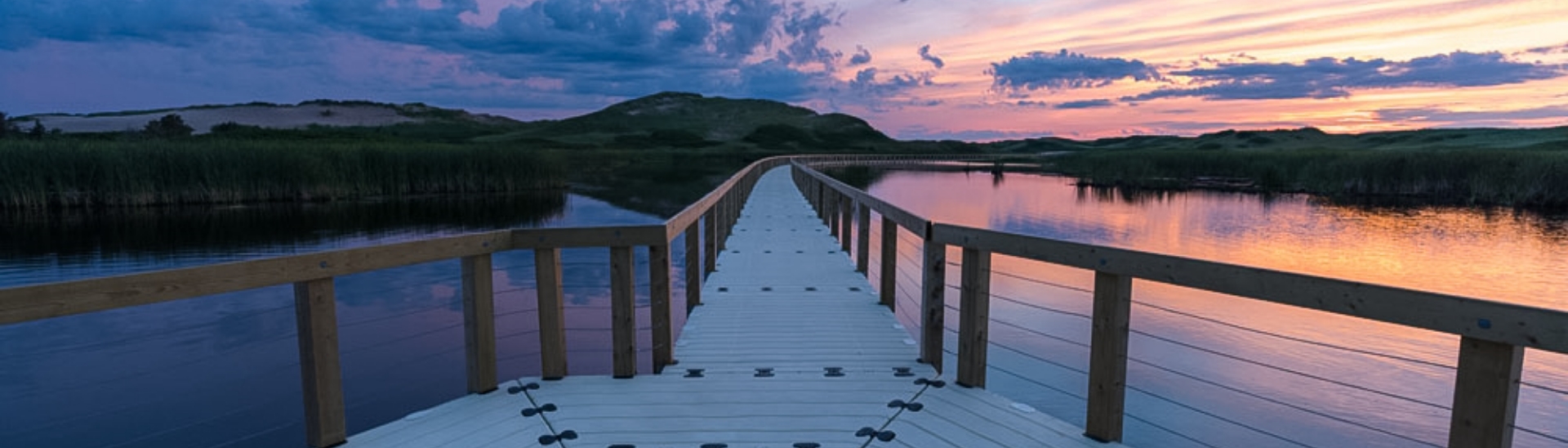 View of floating walkway with wire guardrails at sunset