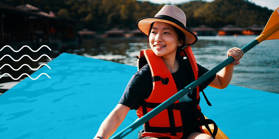 A young female enjoys her kayak while wearing a life vest